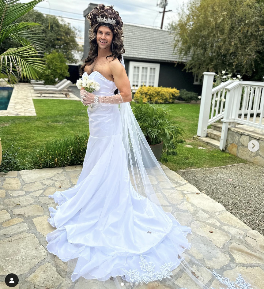 him in a wedding dress and large curly wig with a tiara