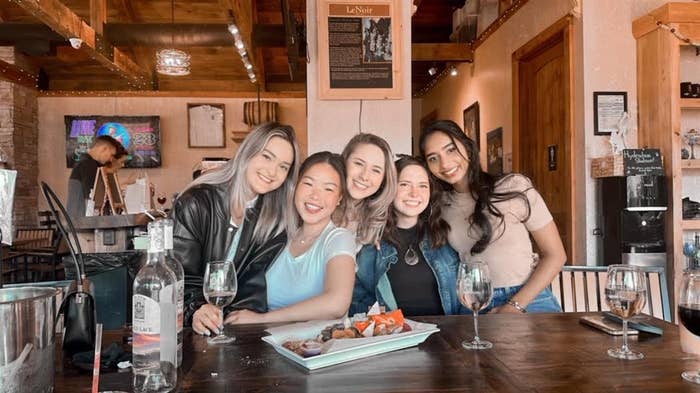 five young women smiling for a photo together at a wine bar
