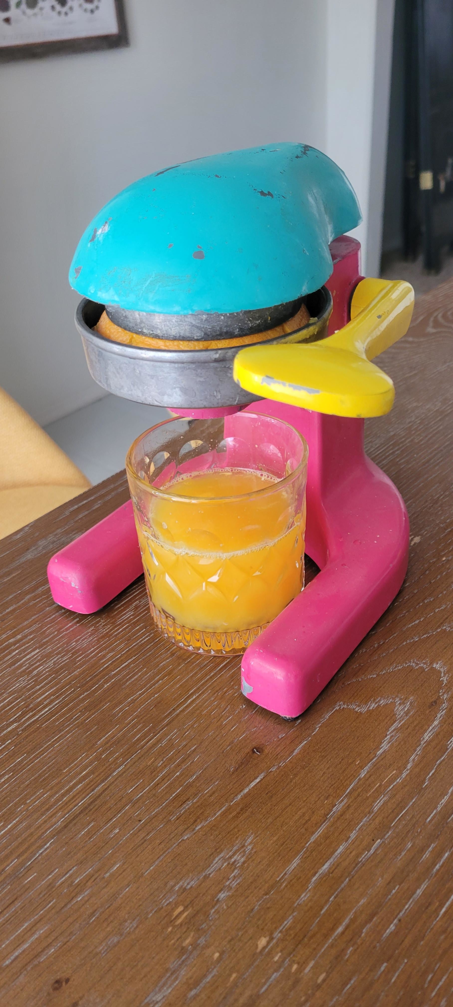 glass of fresh orange juice underneath a juicer
