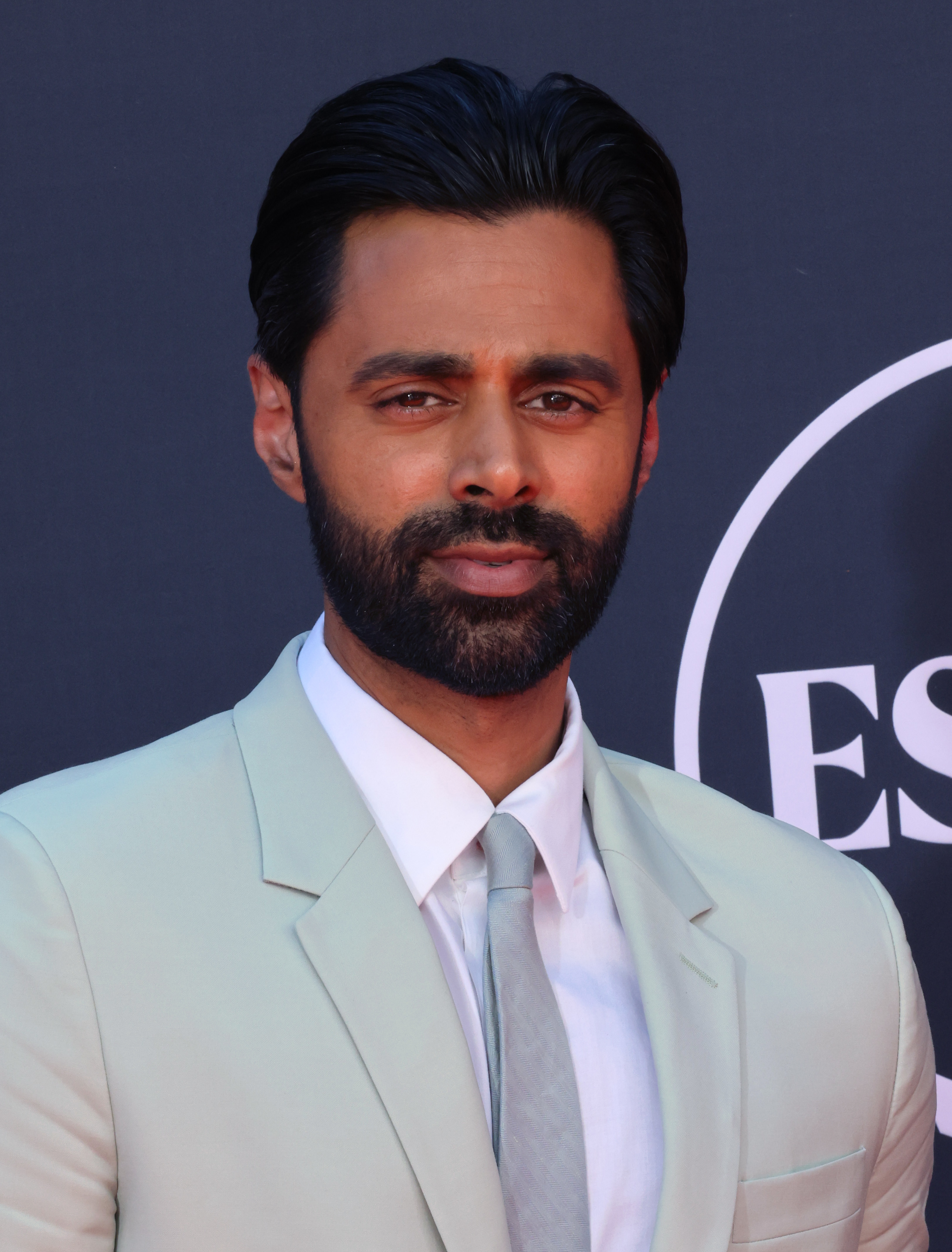 A closeup of Hasan in a suit and tie at an event