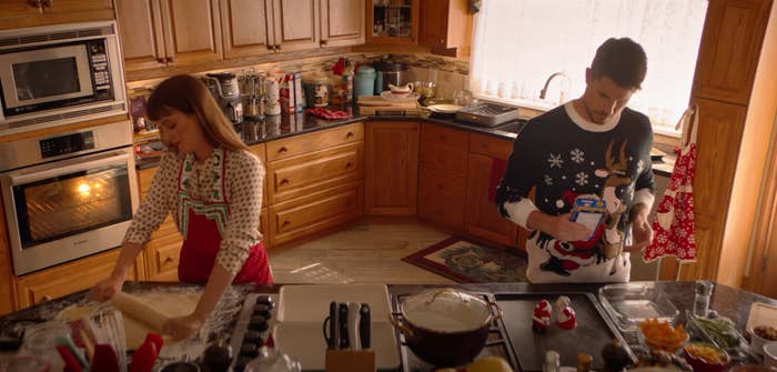 Couple baking together in Christmas sweaters in EXmas movie