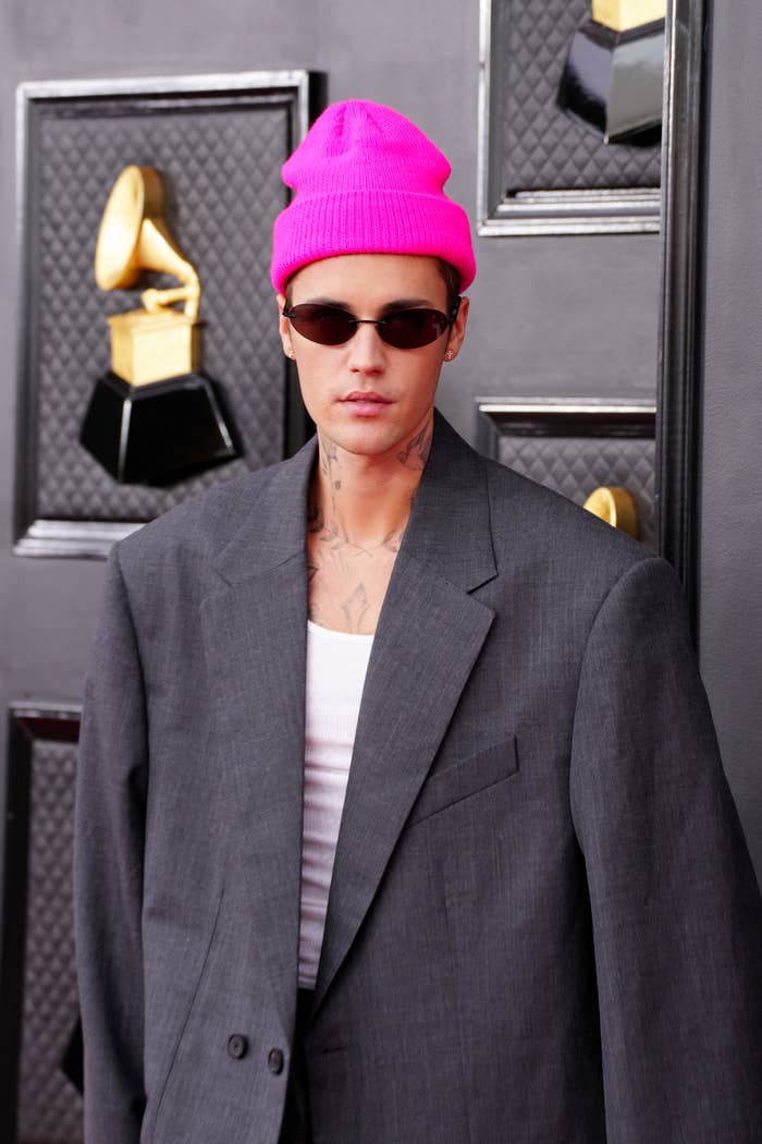 wearing an oversized suit with a bright beanie and sunglasses