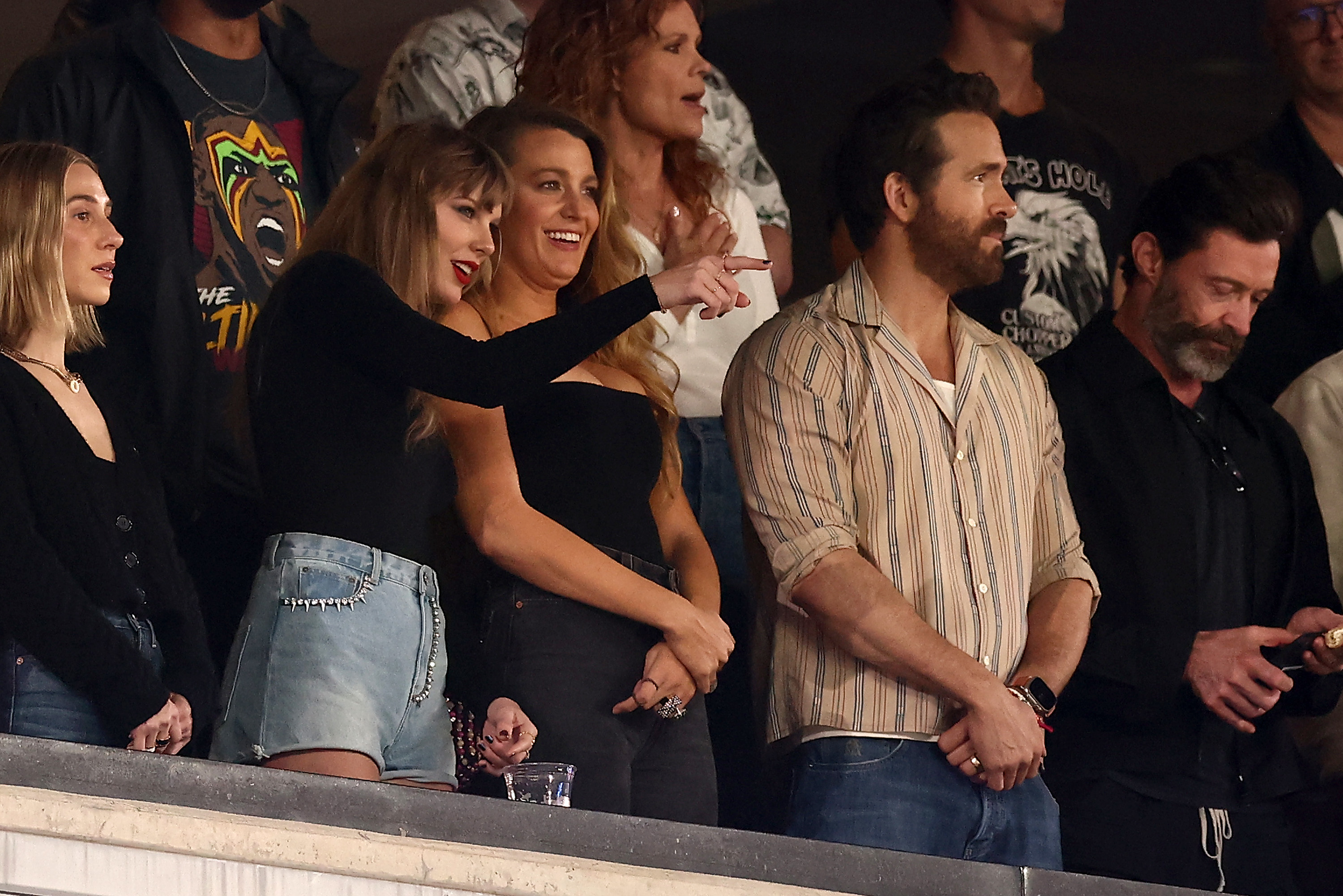 taylor leaning into blake lively and pointing to the field