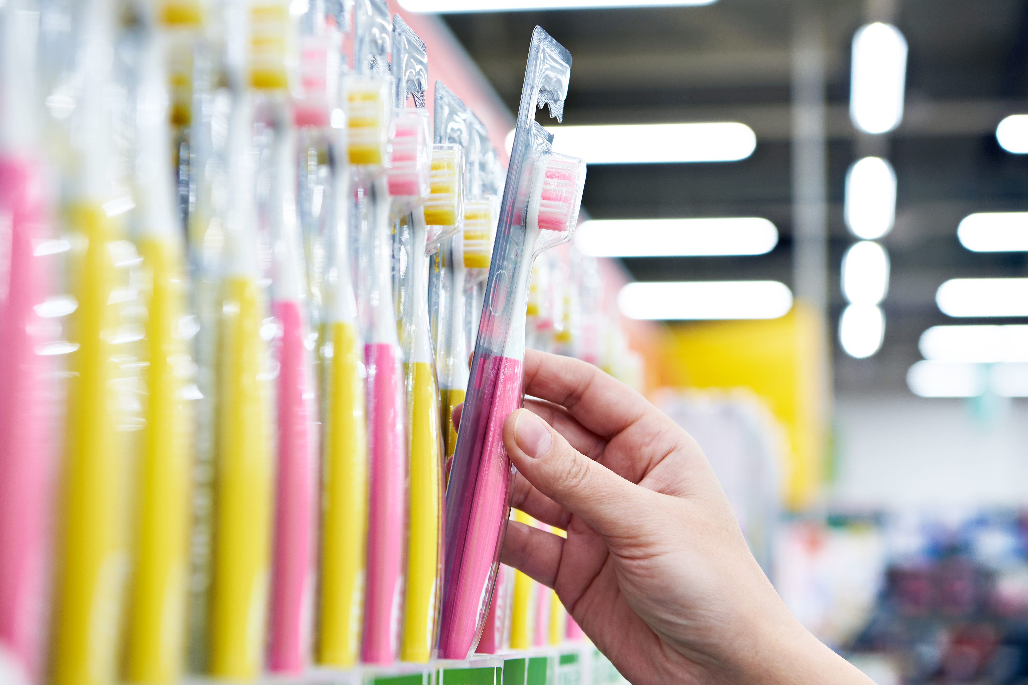 a hand reaching for a new toothbrush off the shelf