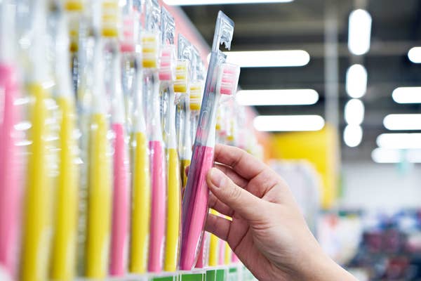 a hand reaching for a new toothbrush off the shelf