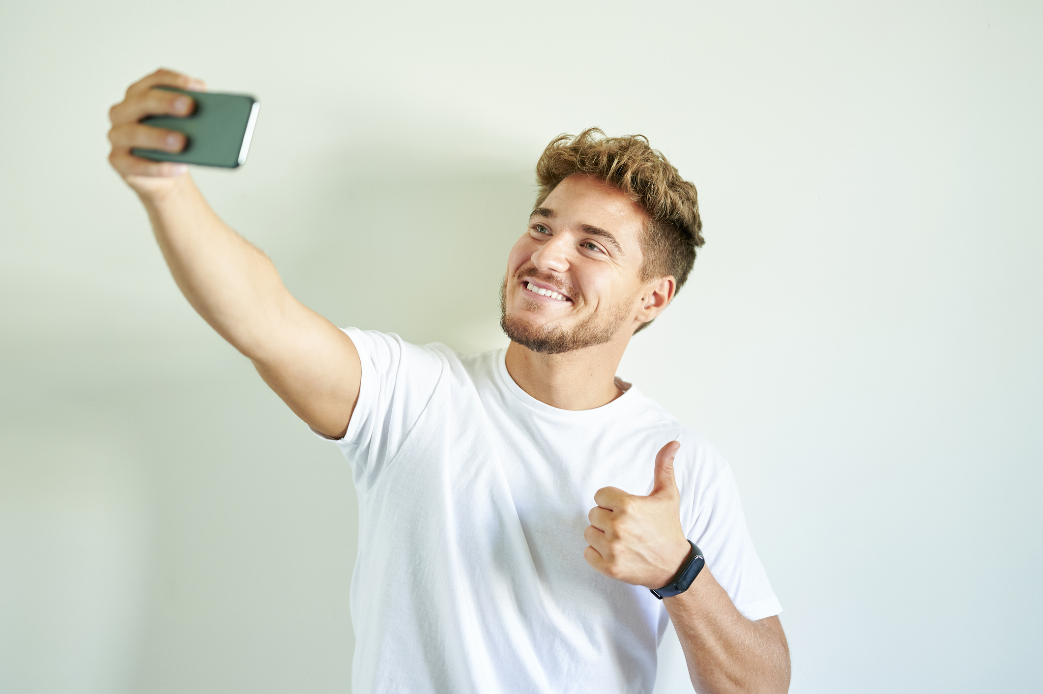 A man taking a selfie with his thumb up
