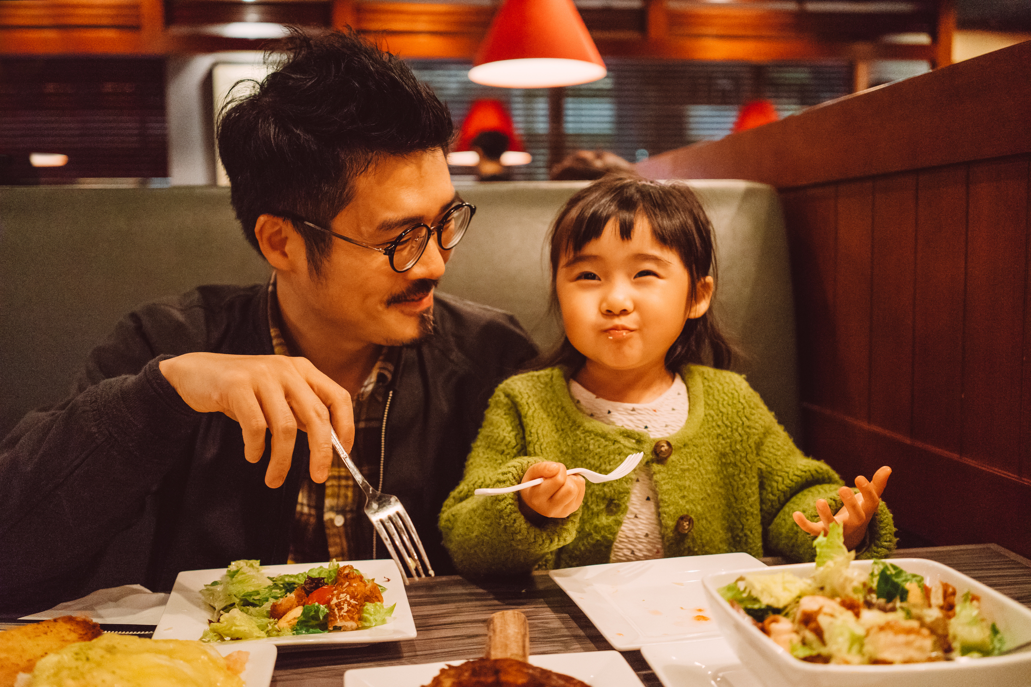 A father and daughter eating in a restaurant