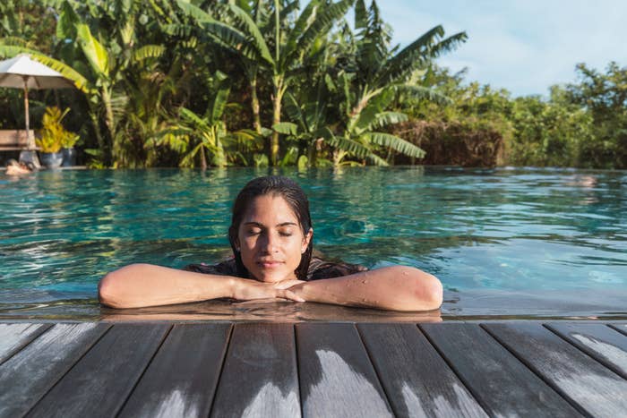 A woman in the water with a lush tropical background behind her