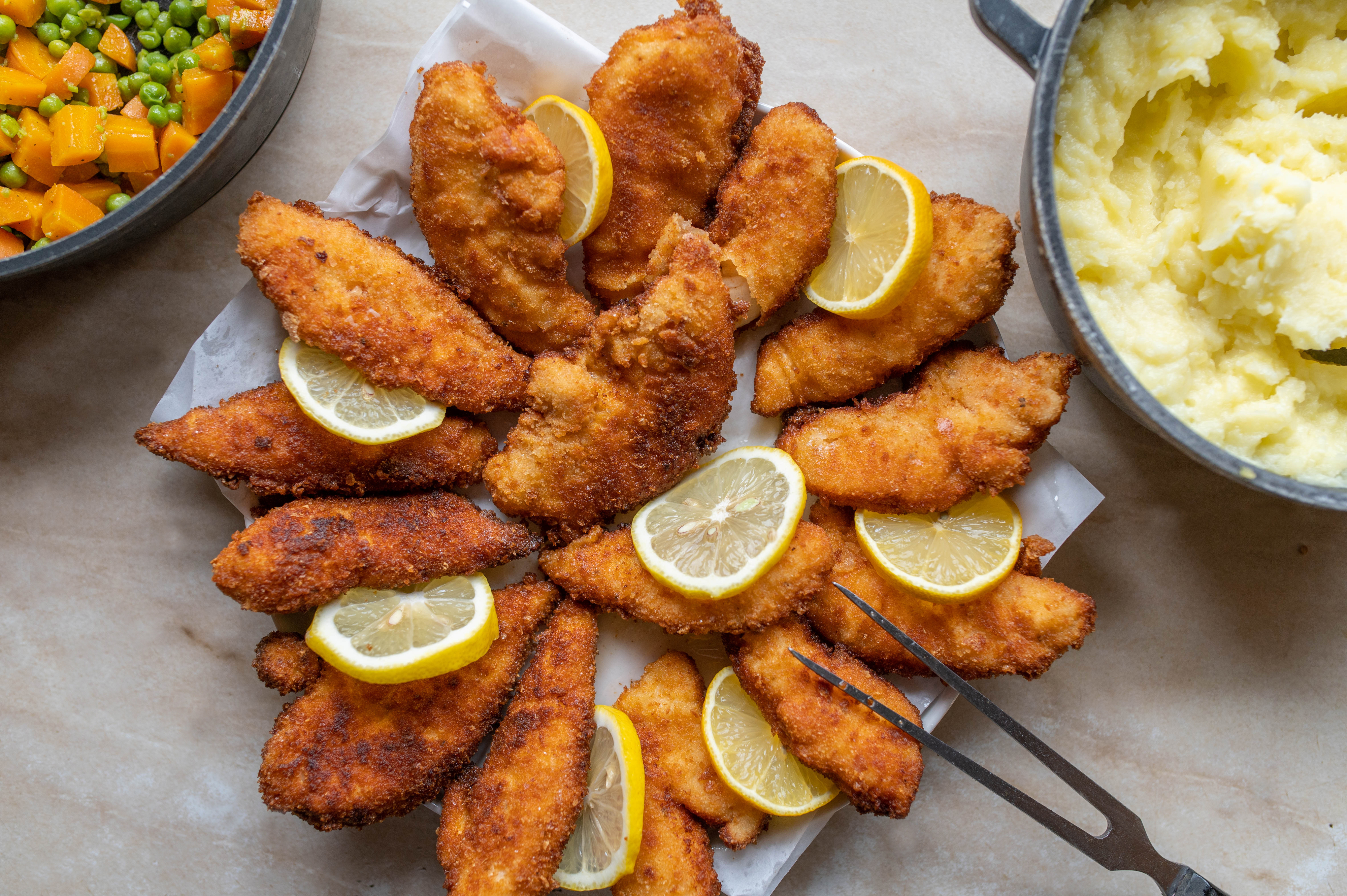 a plate of fried chicken breast and lemon slices