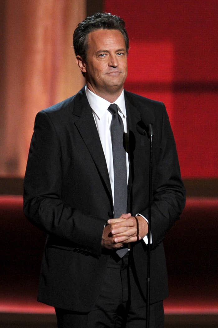 Close-up of Matthew in a suit and tie at a standing microphone