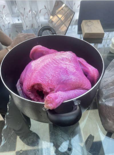A raw turkey in a pot, and the turkey is bright pink