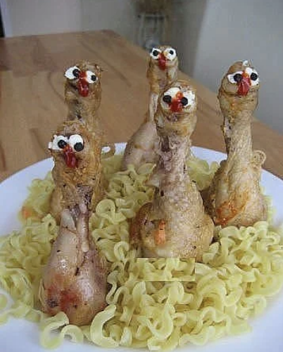A plate of noodles with chicken drumsticks placed in them upside down, and googly eyes drawn on the drumsticks