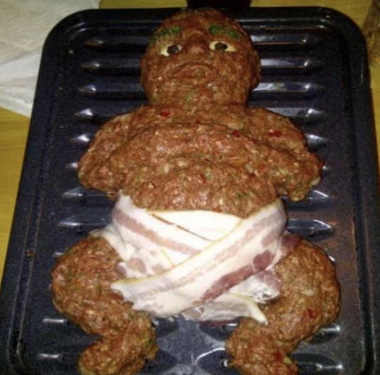 A terrifying-looking clump of raw meat made to look like a baby, with several strips of bacon used as a diaper