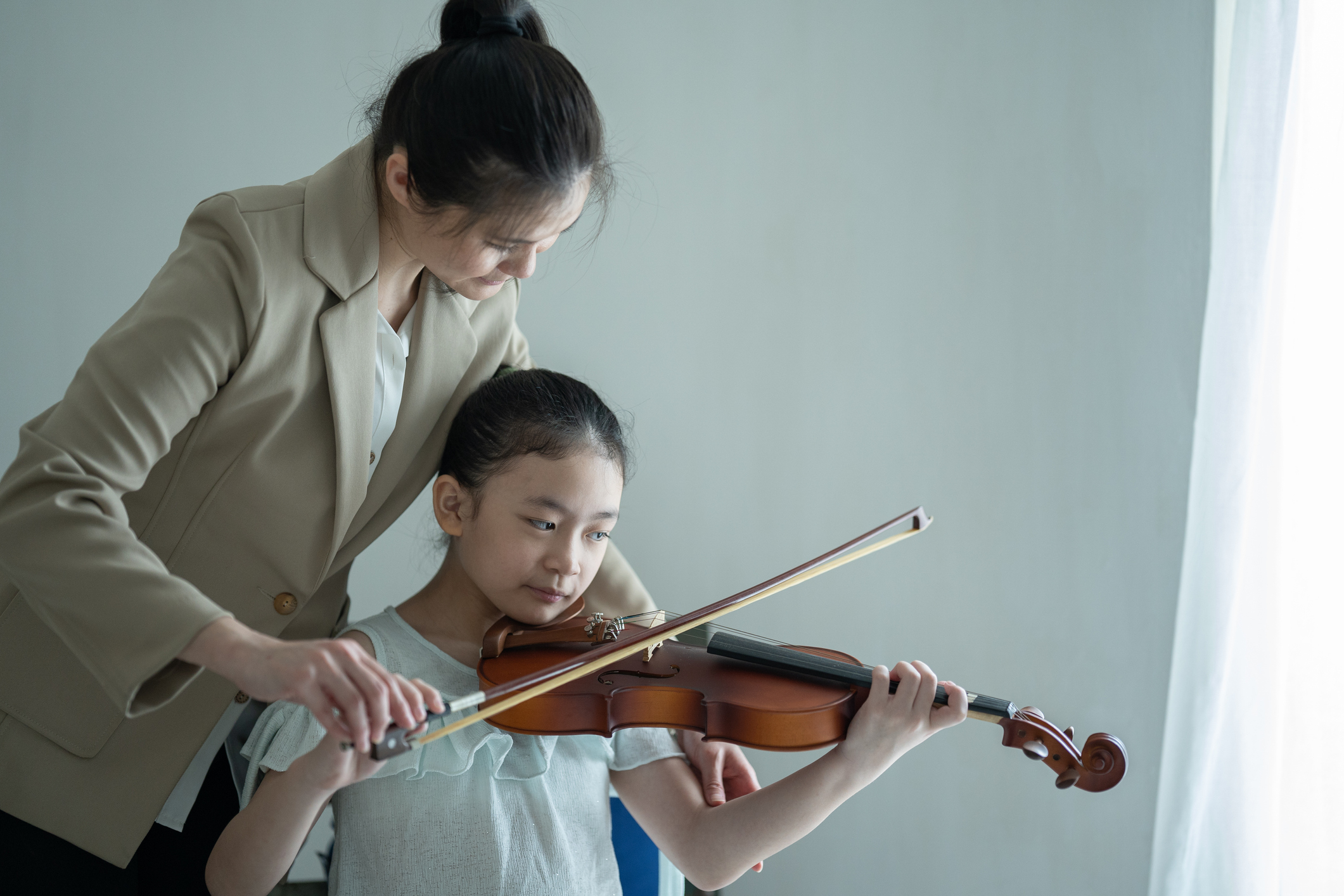 A woman teaching a student how to play violin