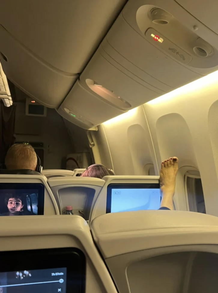 person&#x27;s bare foot on the plane seat