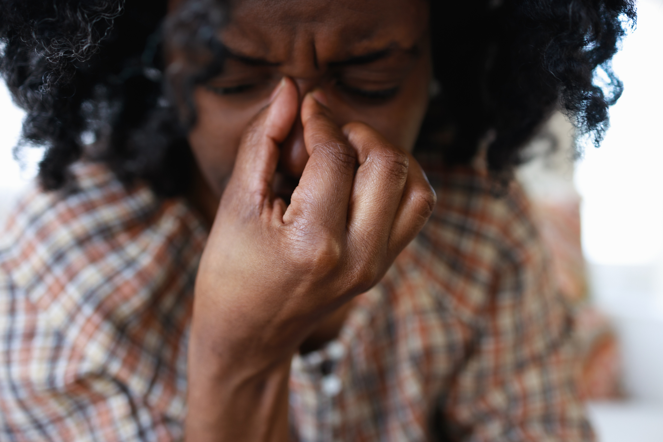A woman pinching her nose in pain