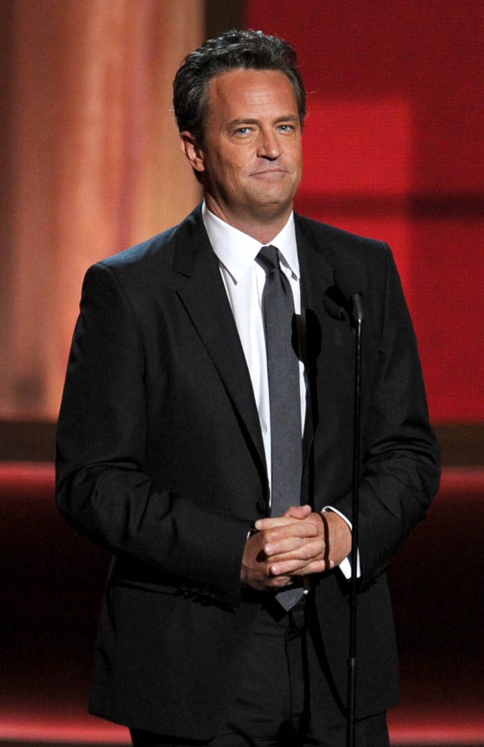 Matthew Perry in a suit and tie onstage