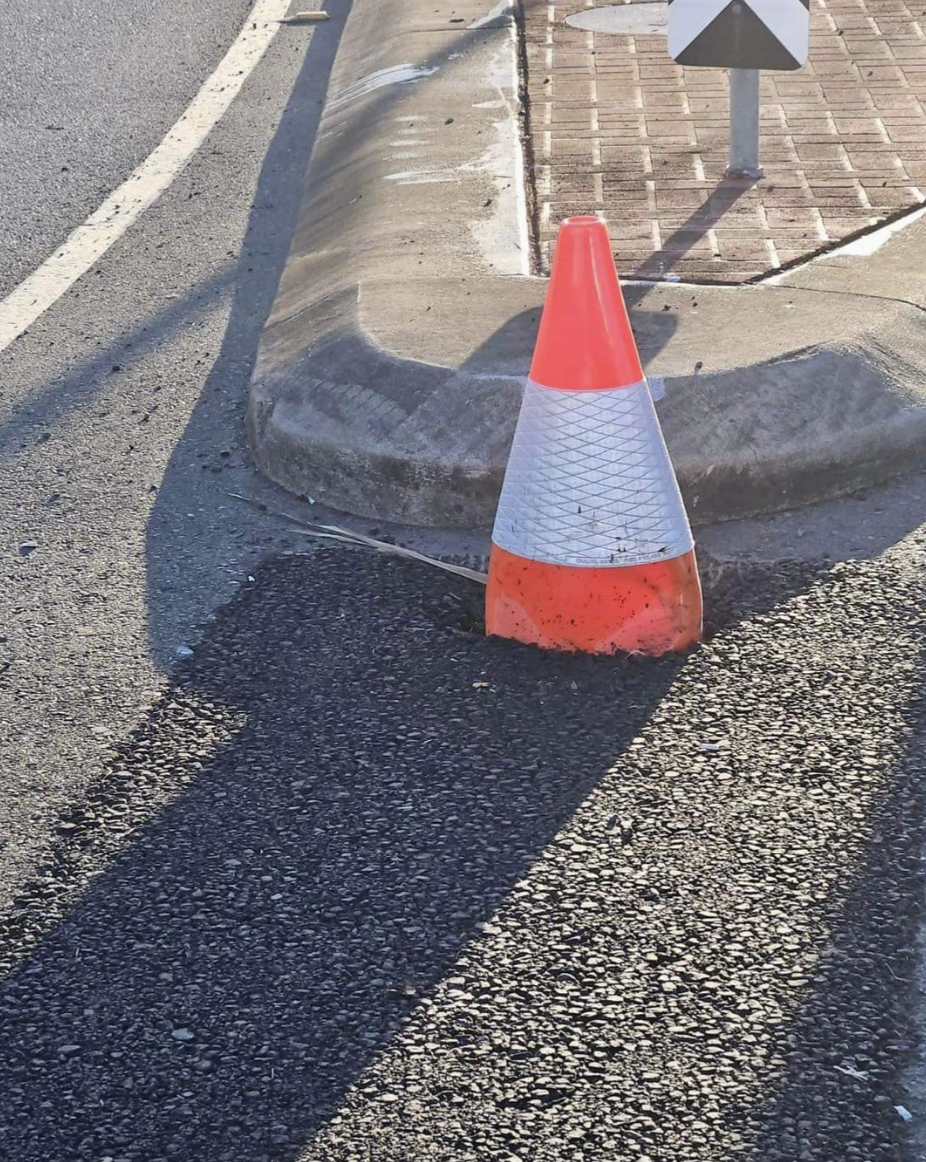 cone has become a part of the street after tar was poured on top