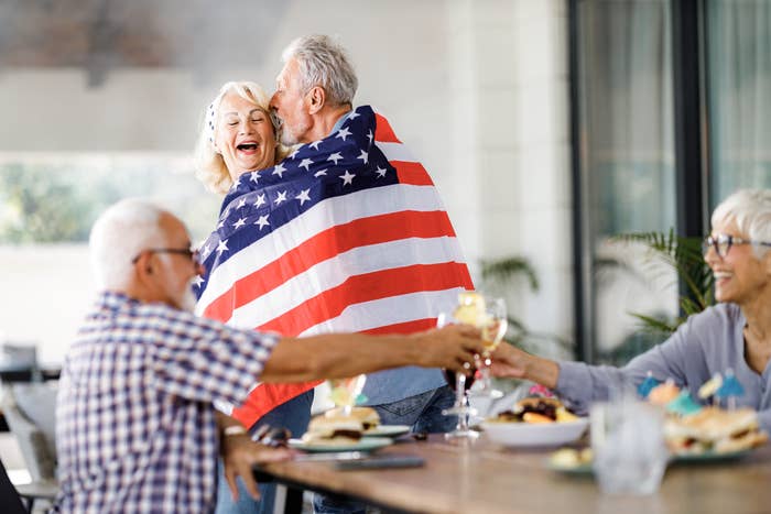 A man kissing a woman while draping themselves in an American flag