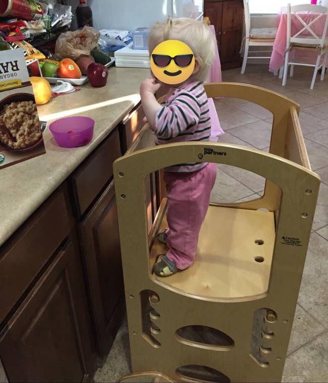 image of reviewer's child standing in the learning tower positioned in front of a kitchen counter