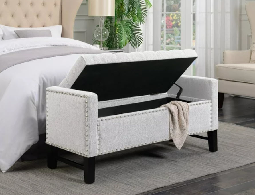 white storage bench with nailhead trim at the end of bed