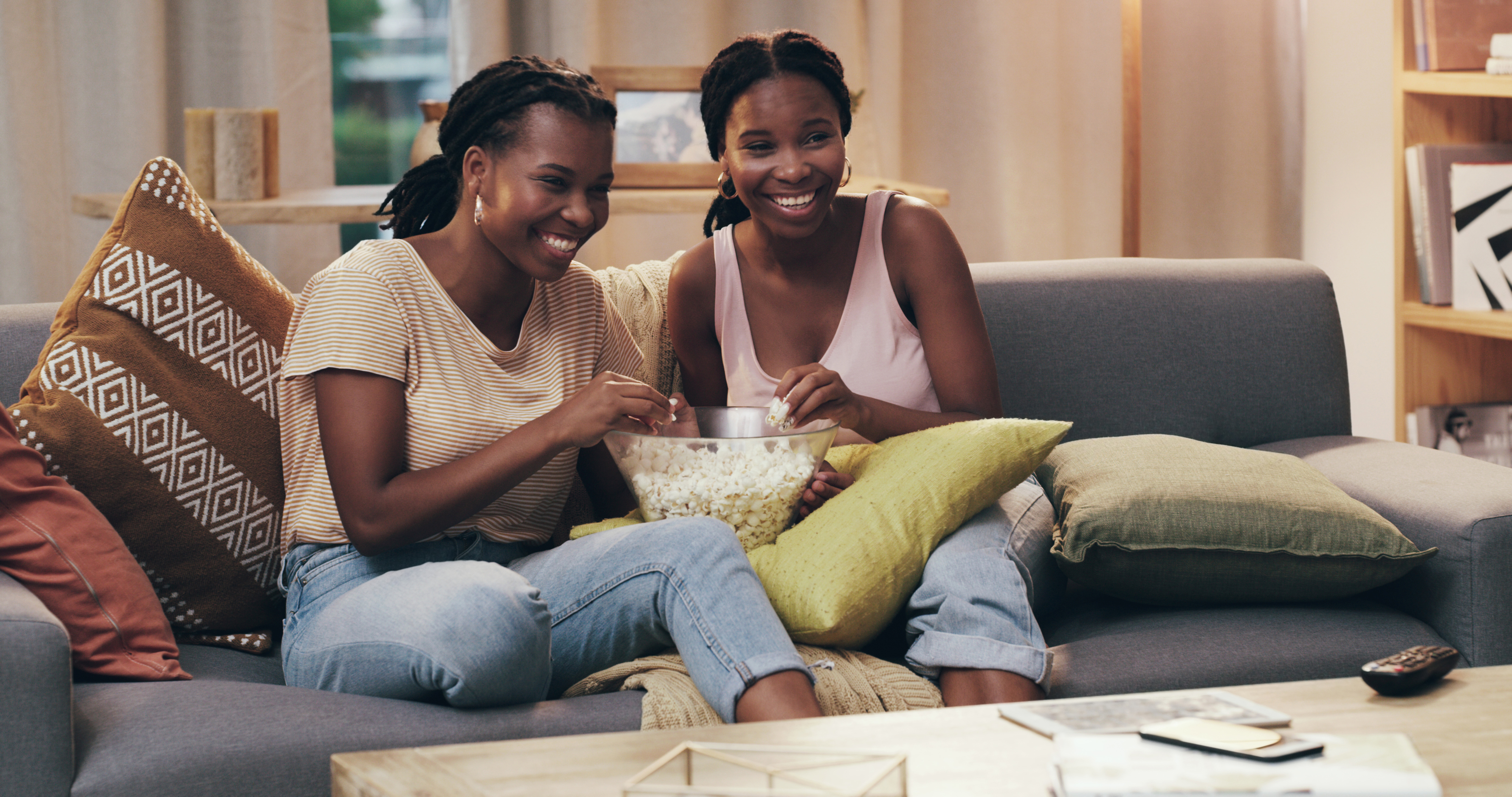 friends sharing a bowl of popcorn on the couch at home