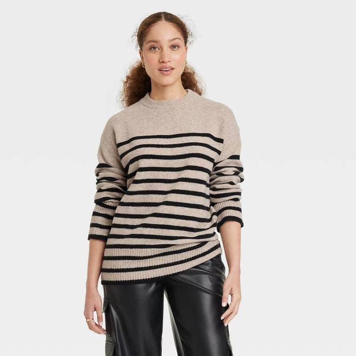 A model wearing the sweater in cream and black strip design