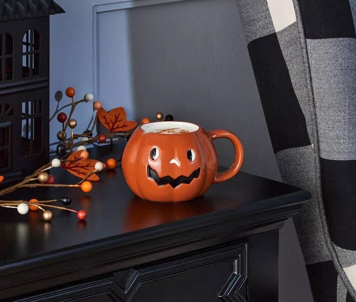 The orange mug, which resembles a jack-o-latern with a handle