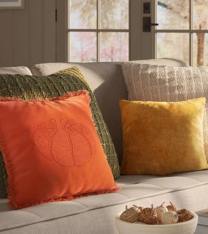the rust-orange pillow with an embroidered pumpkin motif across the center front in the same shade and frayed edges