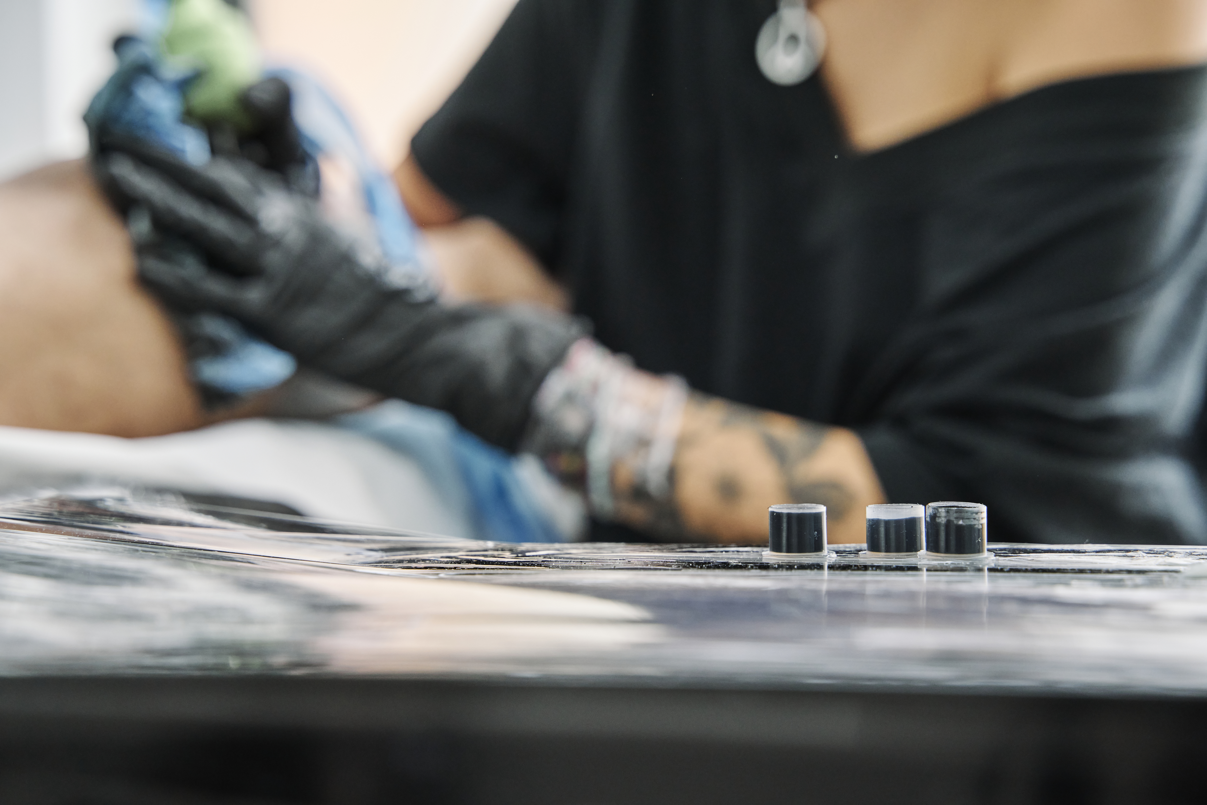 tattoo artist working on client with black ink on table