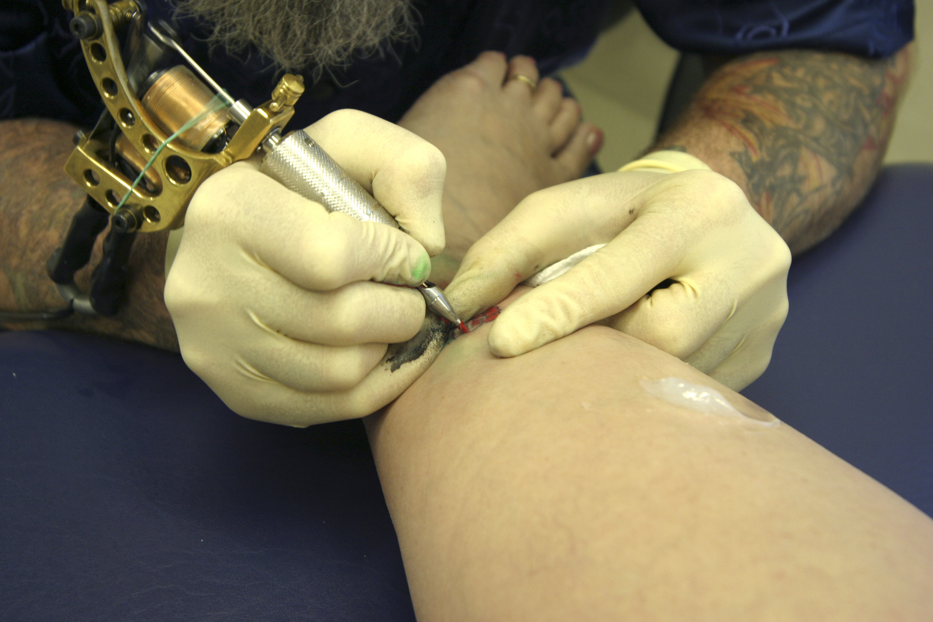 tattoo artist working on woman&#x27;s ankle