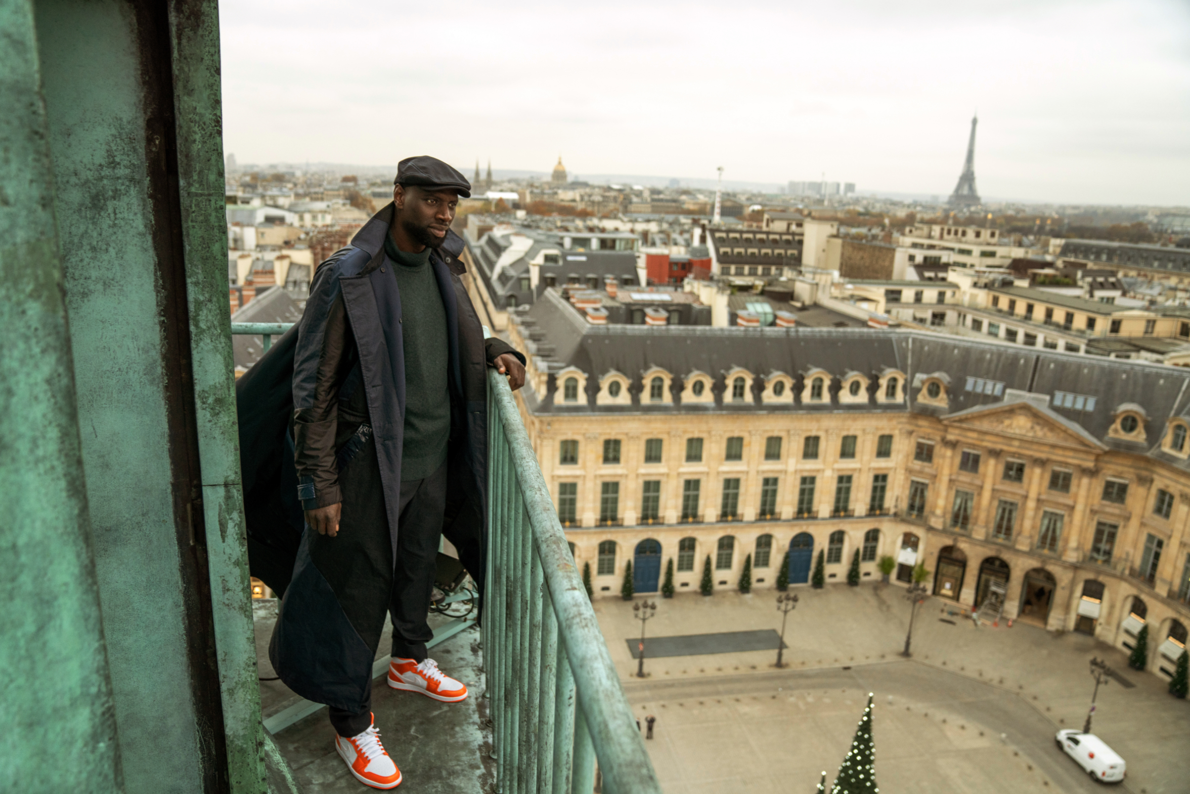 man standing on a balcony overlooking paris