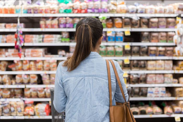 A woman looking at the brea aisle in a grocery store