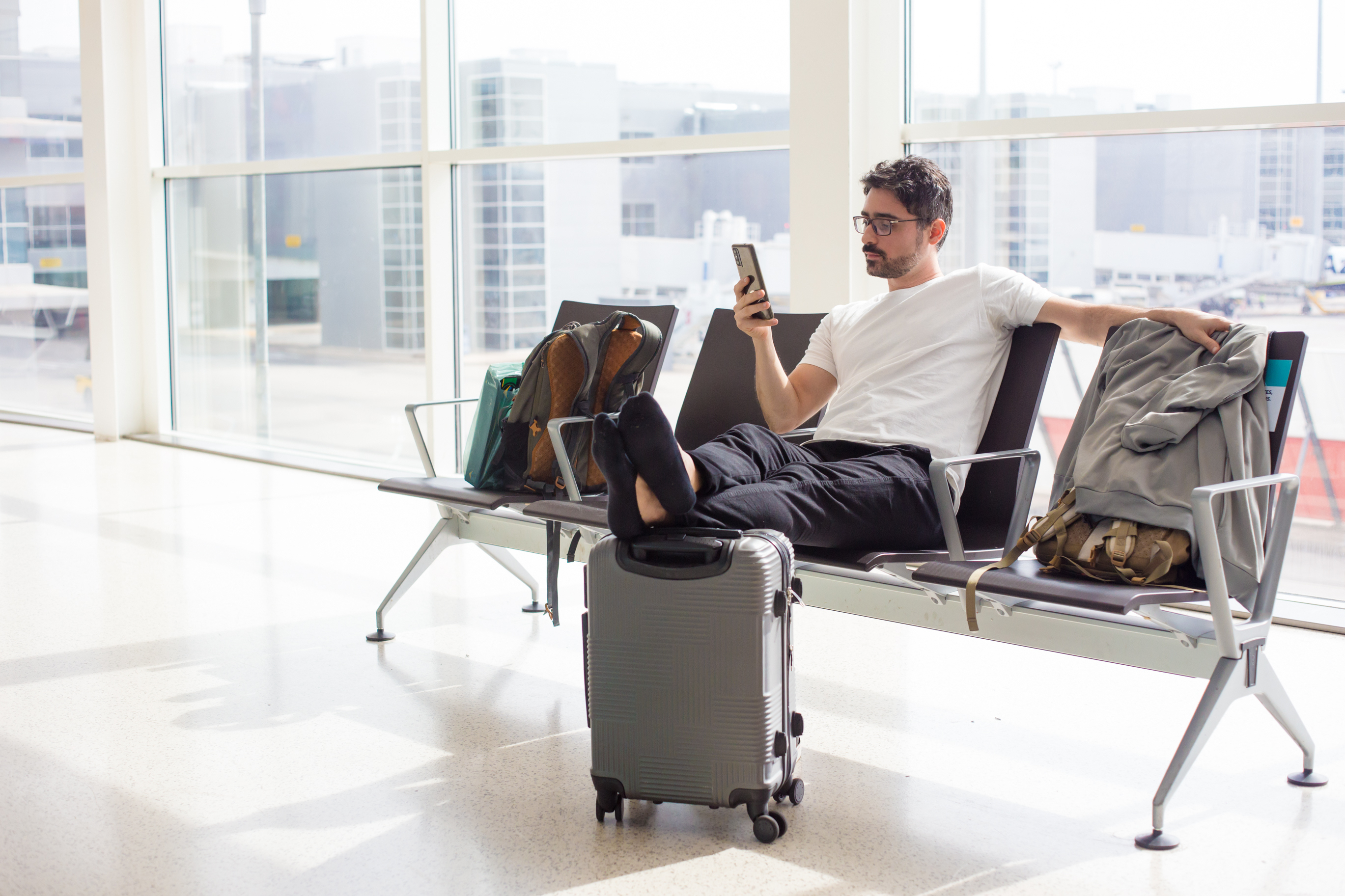 someone sitting in an airport with their feet up on their suitcase