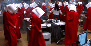 People dressed as &quot;Handmaid&#x27;s Tale&quot; walk in circles through the office.