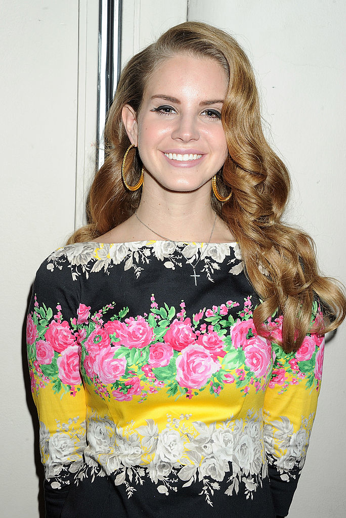 Smiling and wearing big earrings and a floral-print outfit