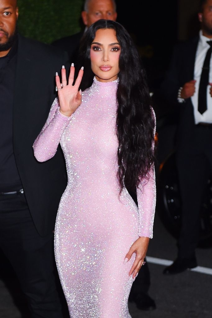 Waving and wearing a shiny bodysuit dress with long sleeves