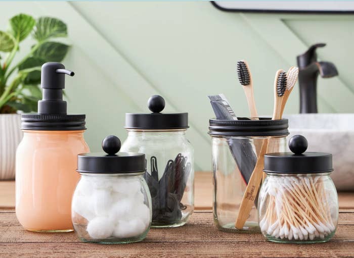 five glass containers filled with bathroom essentials