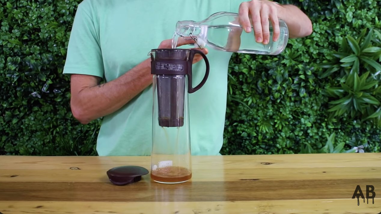 man making cold brew in a cold brew pitcher