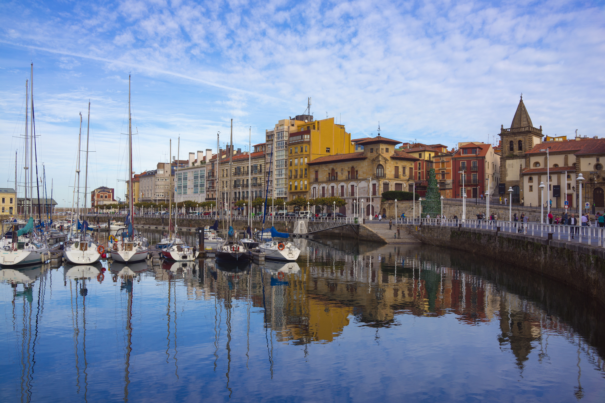 Sailing boats reflected in the water of the city marina in Gijon, Spain