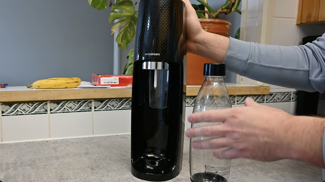person using a sodastream device to make soda at home