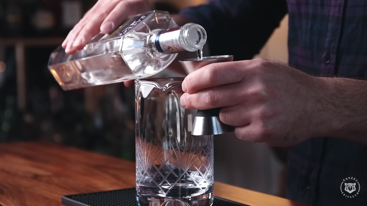 man pouring gin into a cocktail mixing jar