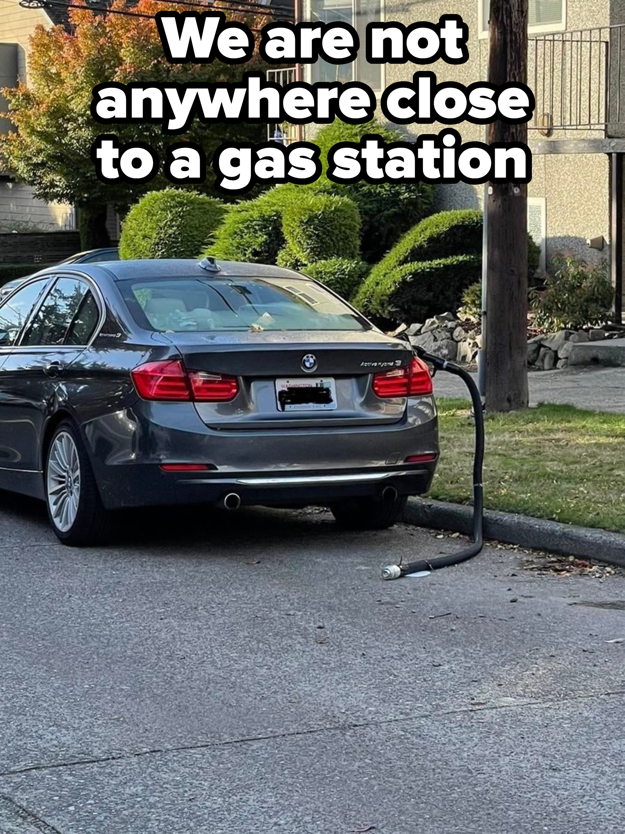 A gas station gas hose dangling out of a car on the road
