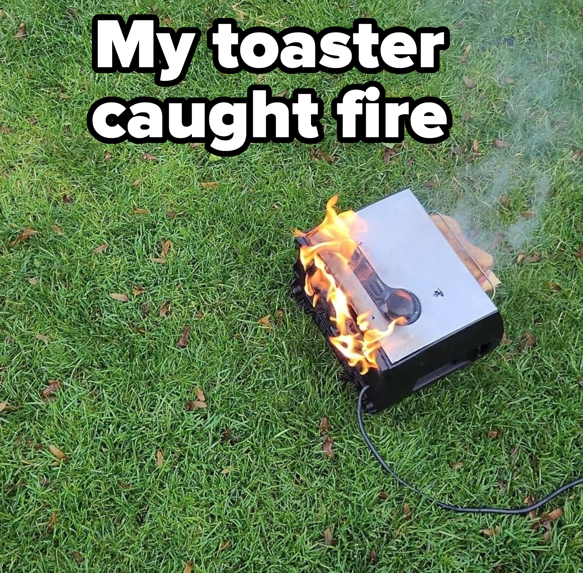 A toaster on fire on the grass