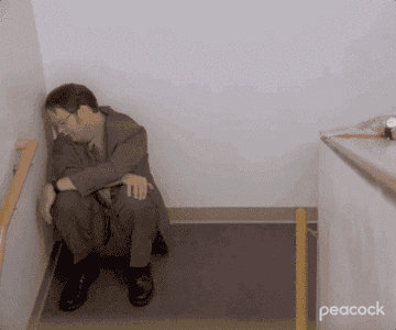 Dwight Shrute cries in the corner of a hallway.