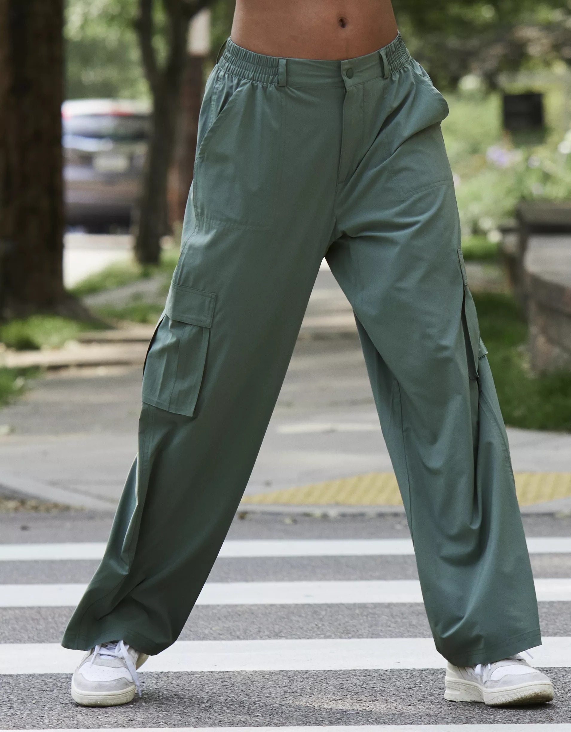 a model wearing the olive green pants on a crosswalk