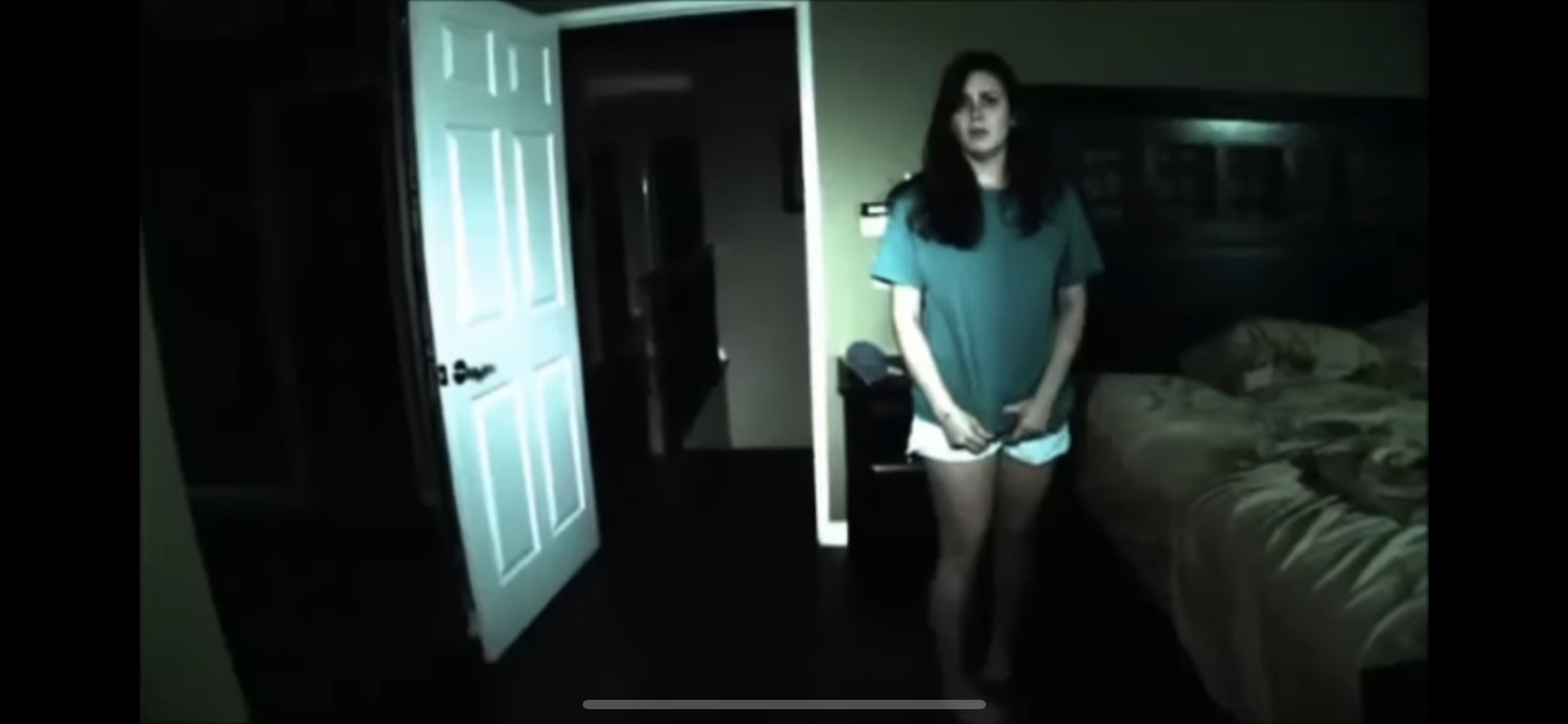 Home video–style footage of woman in pajamas in a bedroom at night