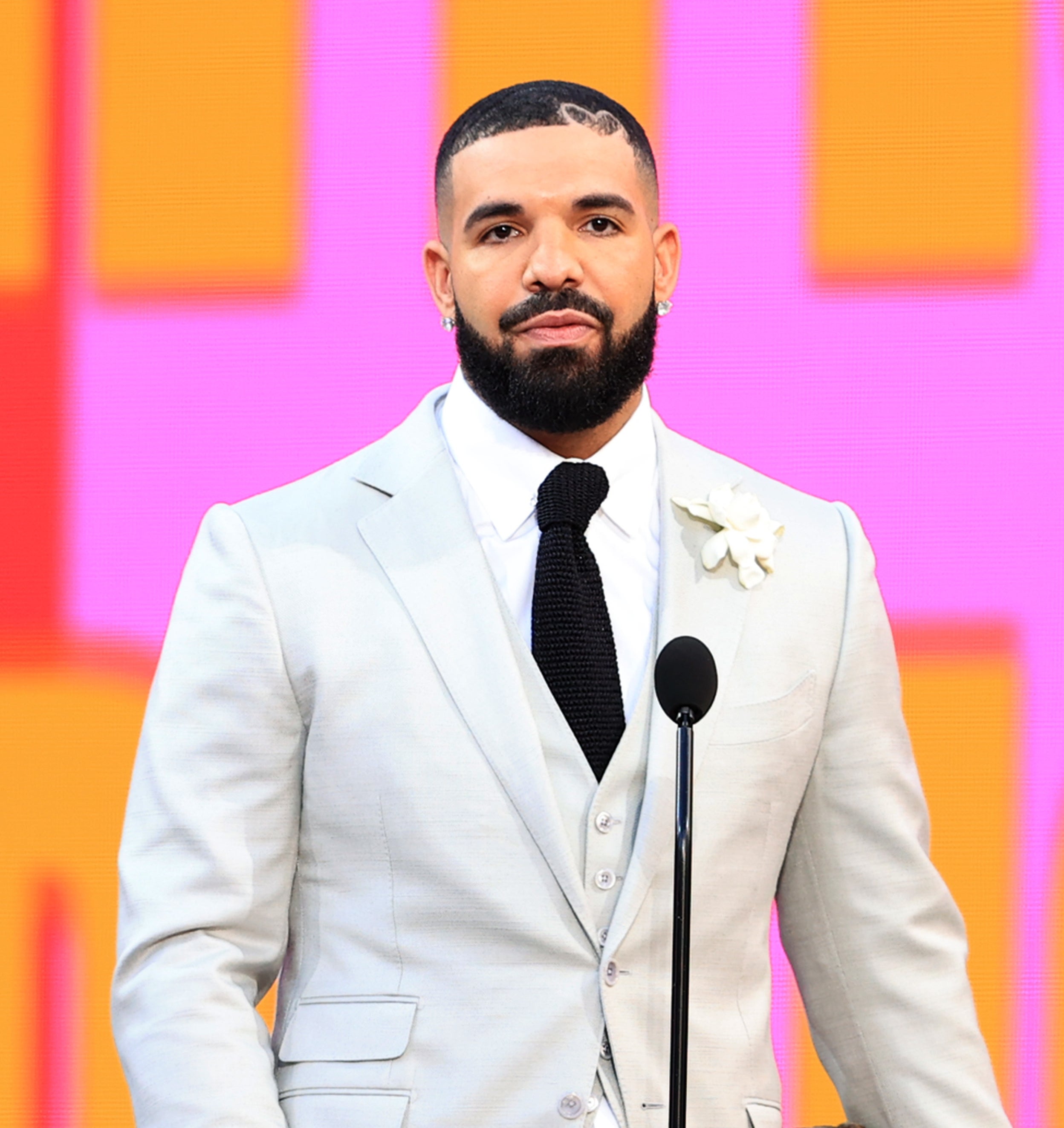 Close-up of Drake in a suit and tie at a microphone