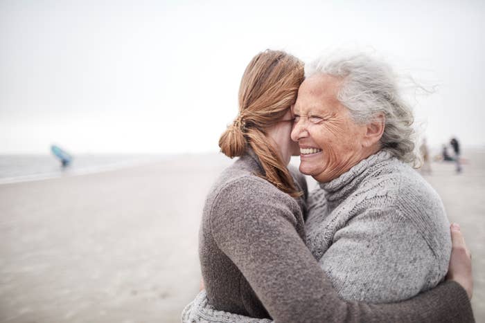 an older woman hugging a young girl on the beach