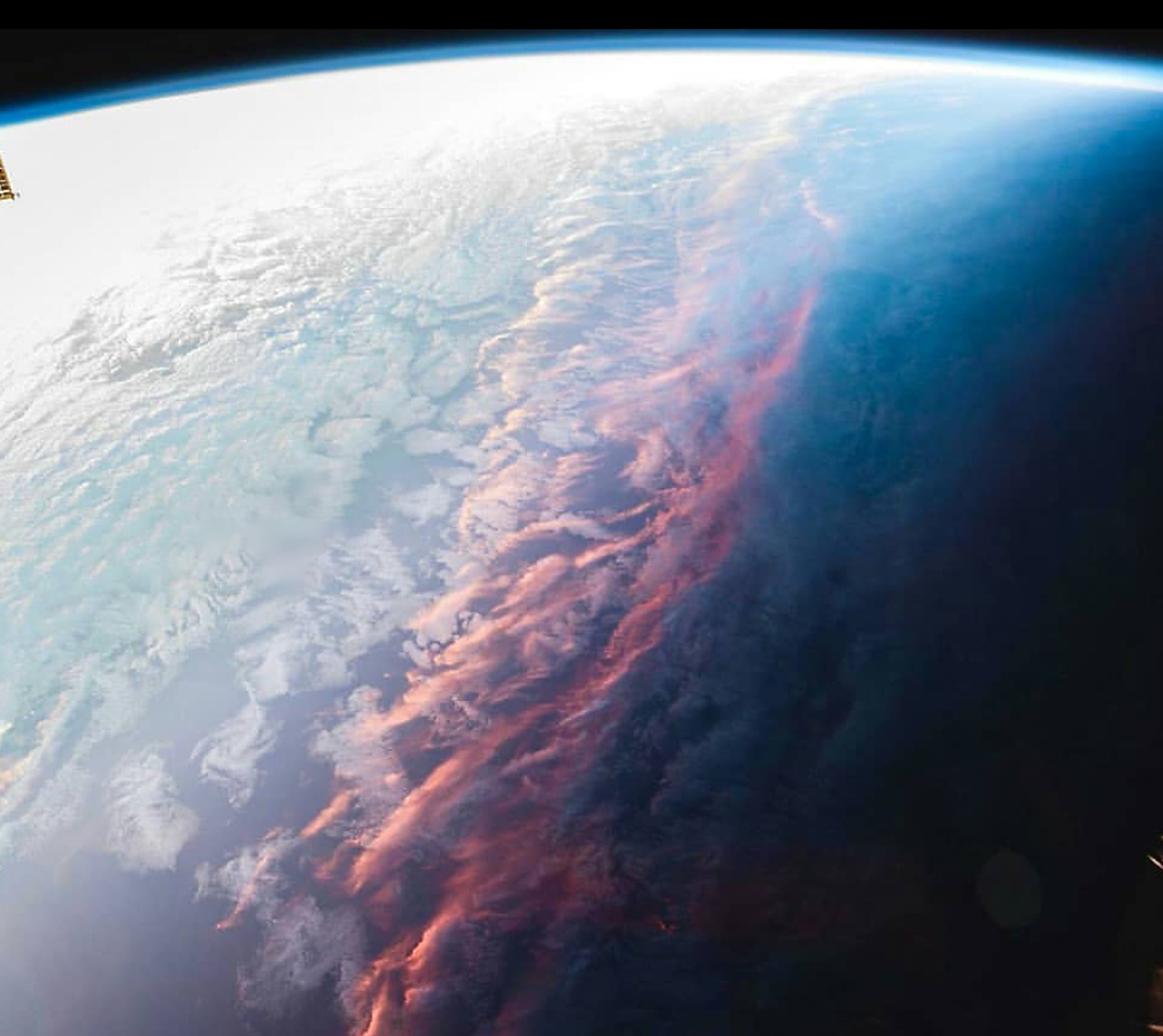 A vertical reddish line among the clouds against the curvature of space